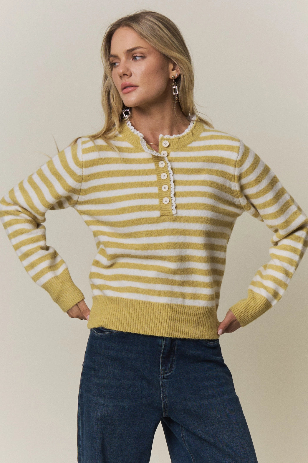 A women's long-sleeve knit henley sweater in mustard yellow and cream horizontal stripes featuring a white eyelet lace trim along the neckline and button placket.