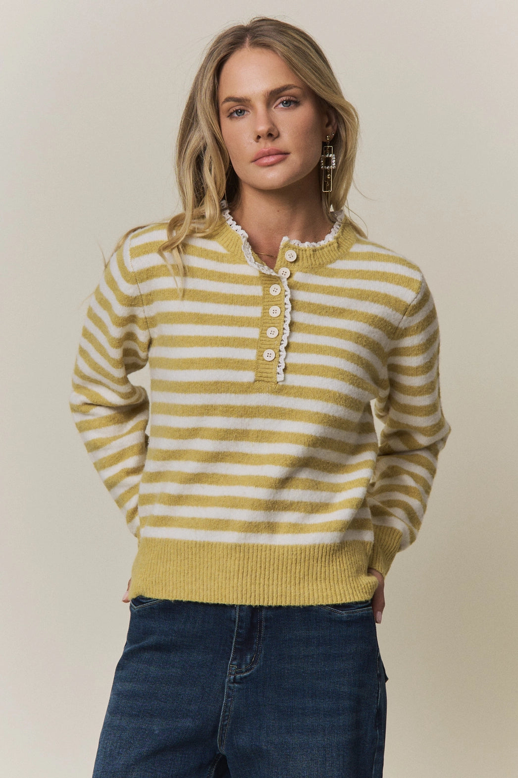 A women's long-sleeve knit henley sweater in mustard yellow and cream horizontal stripes featuring a white eyelet lace trim along the neckline and button placket.