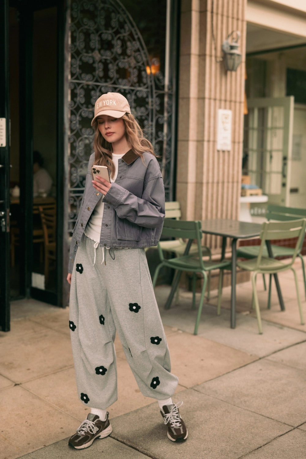 A women's heather gray wide-leg fleece sweatpants featuring an elastic drawstring waistband, relaxed barrel leg, and black chenille flower patches across the front and back.