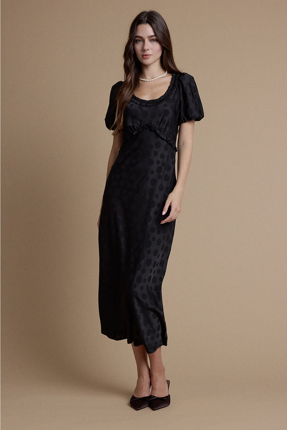 A women's black satin jacquard polka dot midi dress featuring short puff sleeves, a scoop neckline with ruffle trim, and a high empire waistline.