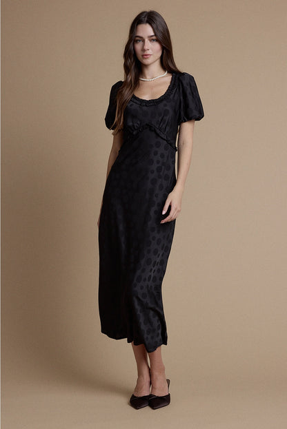 A women's black satin jacquard polka dot midi dress featuring short puff sleeves, a scoop neckline with ruffle trim, and a high empire waistline.