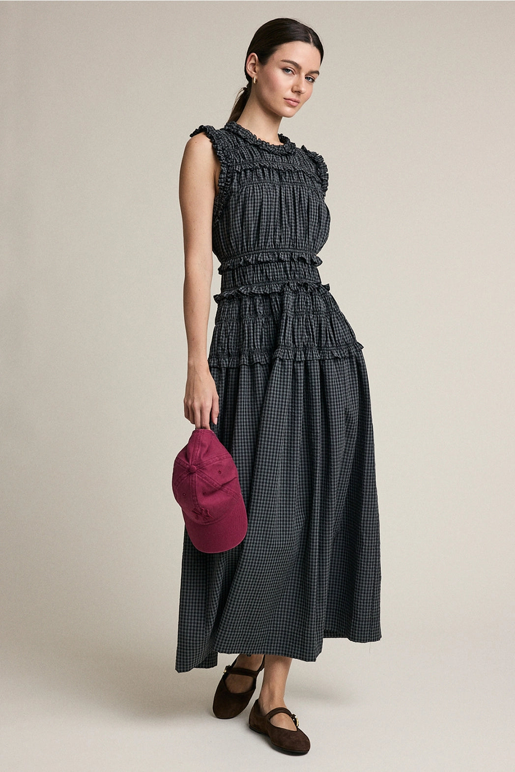 A women's sleeveless maxi dress in a dark gray and black plaid pattern featuring a high ruffled neckline, a fully elasticized smocked bodice, and a flowing tiered skirt with delicate ruffle trim.
