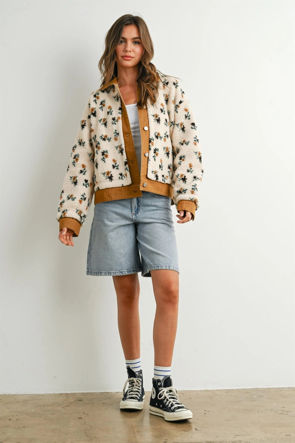A women's cream floral printed plush sherpa fleece jacket featuring camel brown twill contrast trim, front button closures, and side pockets.