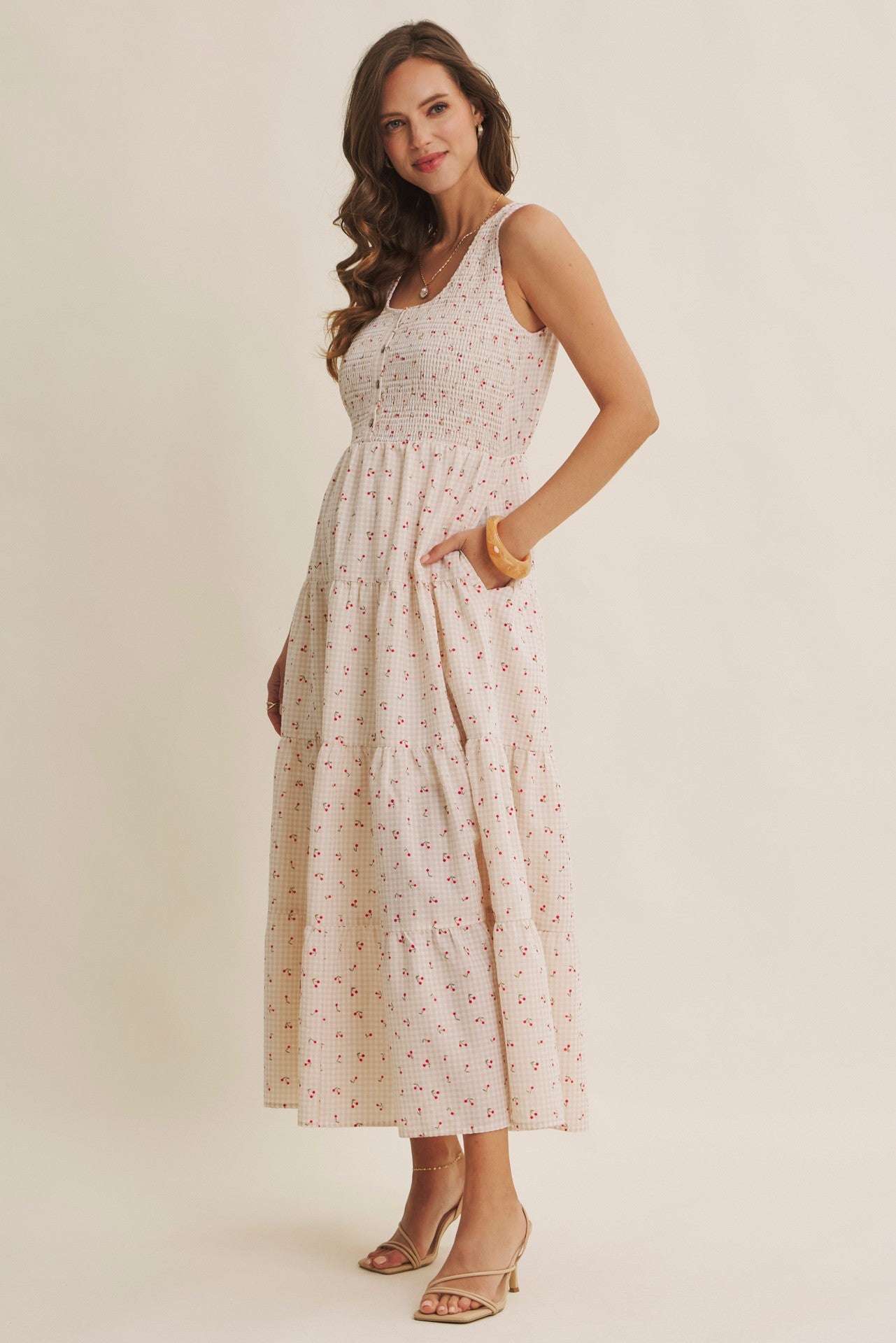 Cherry gingham print maxi dress in the color biscuit. The dress has a smocked bust, round neck, button-down detail, side pockets and comes lined. 