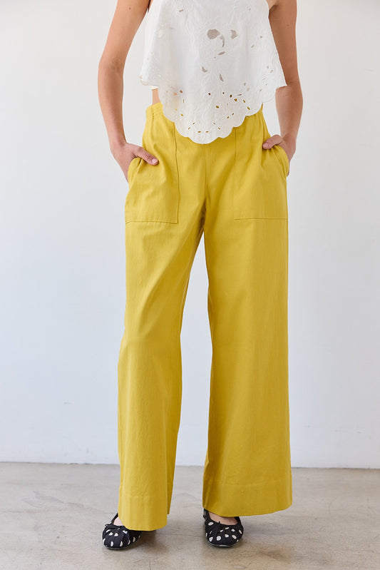 Mustard yellow wide-leg pants featuring a high-rise elastic waistband, a relaxed flowy silhouette, and two functional front patch pockets.