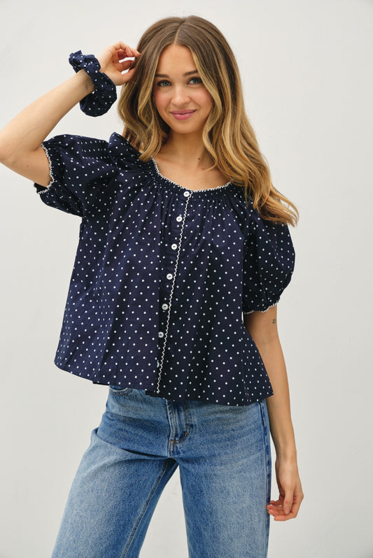 Navy base with white polka dot blouse. With a scoop neckline with white embroidered trim, puff sleeves, lightweight, and flowy fit. 