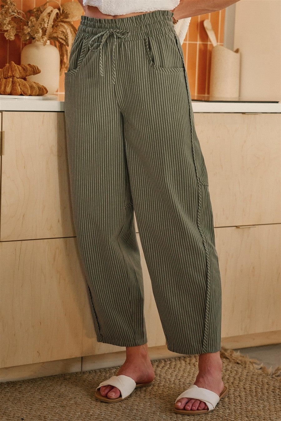 Olive and oatmeal vertical striped linen-blend pants featuring a high-rise elastic drawstring waistband, a relaxed tapered leg, and functional side utility pockets.