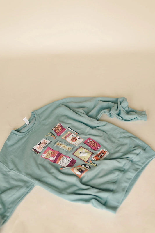 A women's light sage green crewneck pullover sweatshirt featuring vintage-inspired colorful Halloween matchbox illustrations and relaxed drop shoulders.