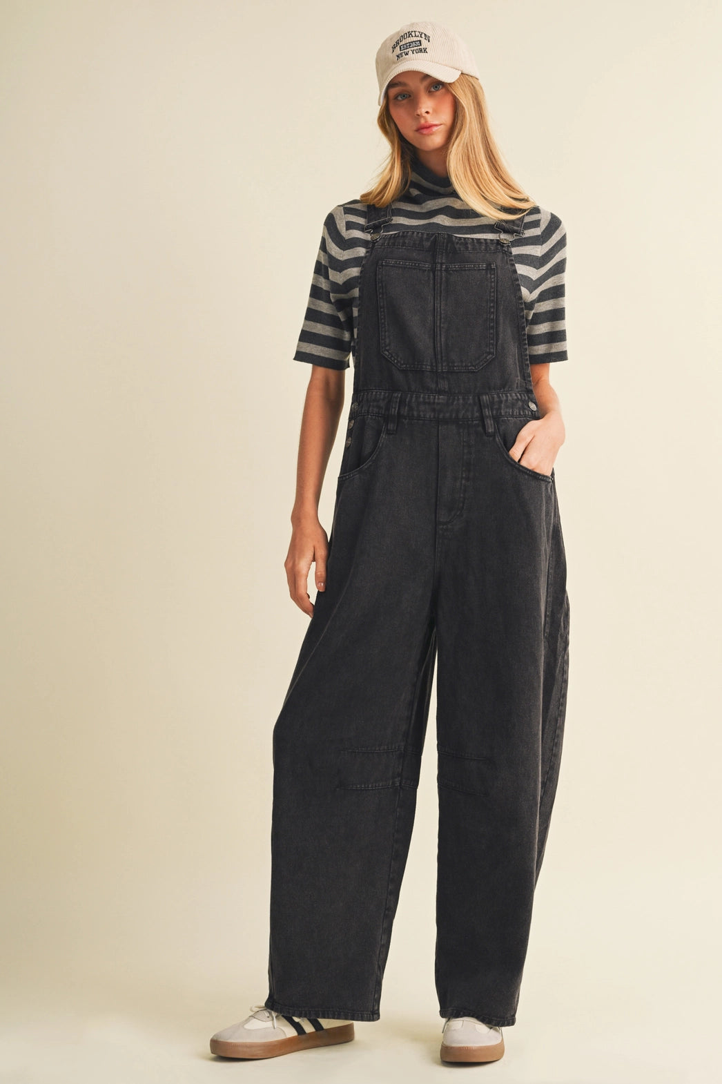 A pair of women's high-waisted wide-leg twill overalls in a vintage washed black denim finish featuring classic adjustable shoulder straps, a front chest pocket, and side pockets.