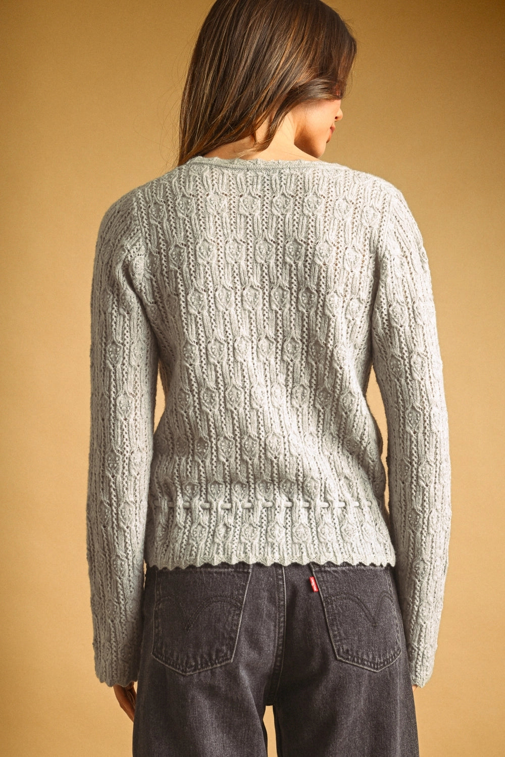 A women's light gray long-sleeve textured lace knit cardigan sweater featuring a button-down front, scalloped V-neckline, and an adjustable drawstring tie waistline.