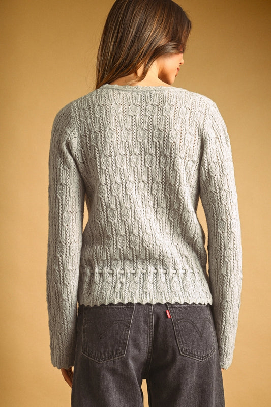 A women's light gray long-sleeve textured lace knit cardigan sweater featuring a button-down front, scalloped V-neckline, and an adjustable drawstring tie waistline.