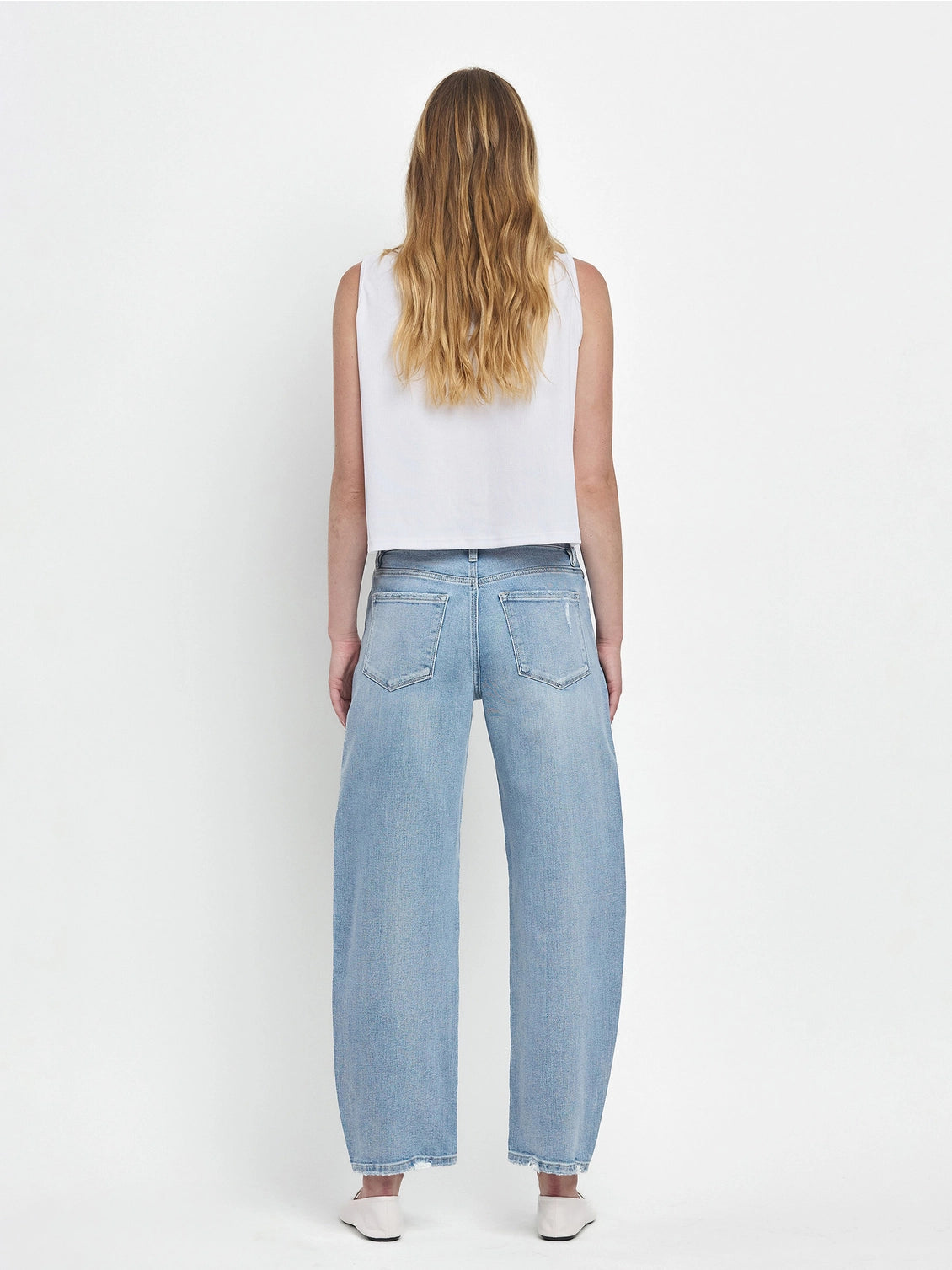 Women's light wash high-rise barrel leg jeans featuring a relaxed curved silhouette, subtle distressing, and an ankle-length hem.