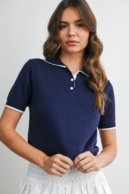 A women's navy blue short-sleeve fine-knit polo top featuring white scalloped contrast trim on the collar, button placket, and sleeve cuffs.