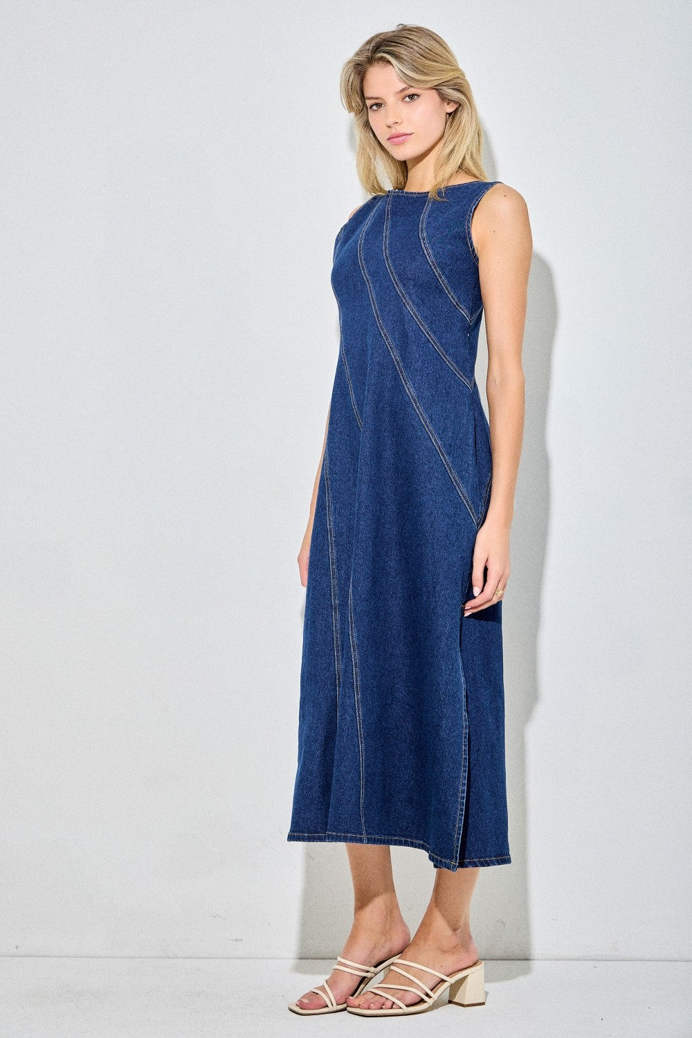 Sleeveless dark denim dress with angle detailing and a side slit. 