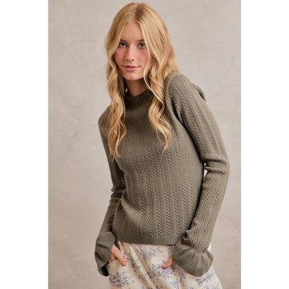 A women's olive green long-sleeve cable-knit sweater featuring a mock neckline, ribbed hem, and ruffled flare knit cuffs.