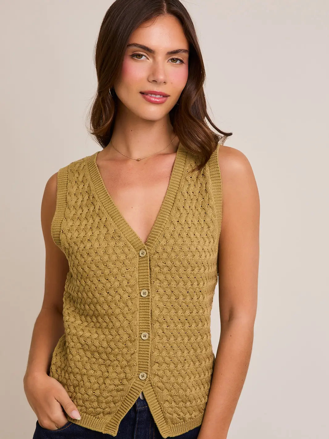 A women's sleeveless olive green button-front vest knit top featuring an intricate textured basketweave pattern, a modest V-neckline, and ribbed trim along the split hem.