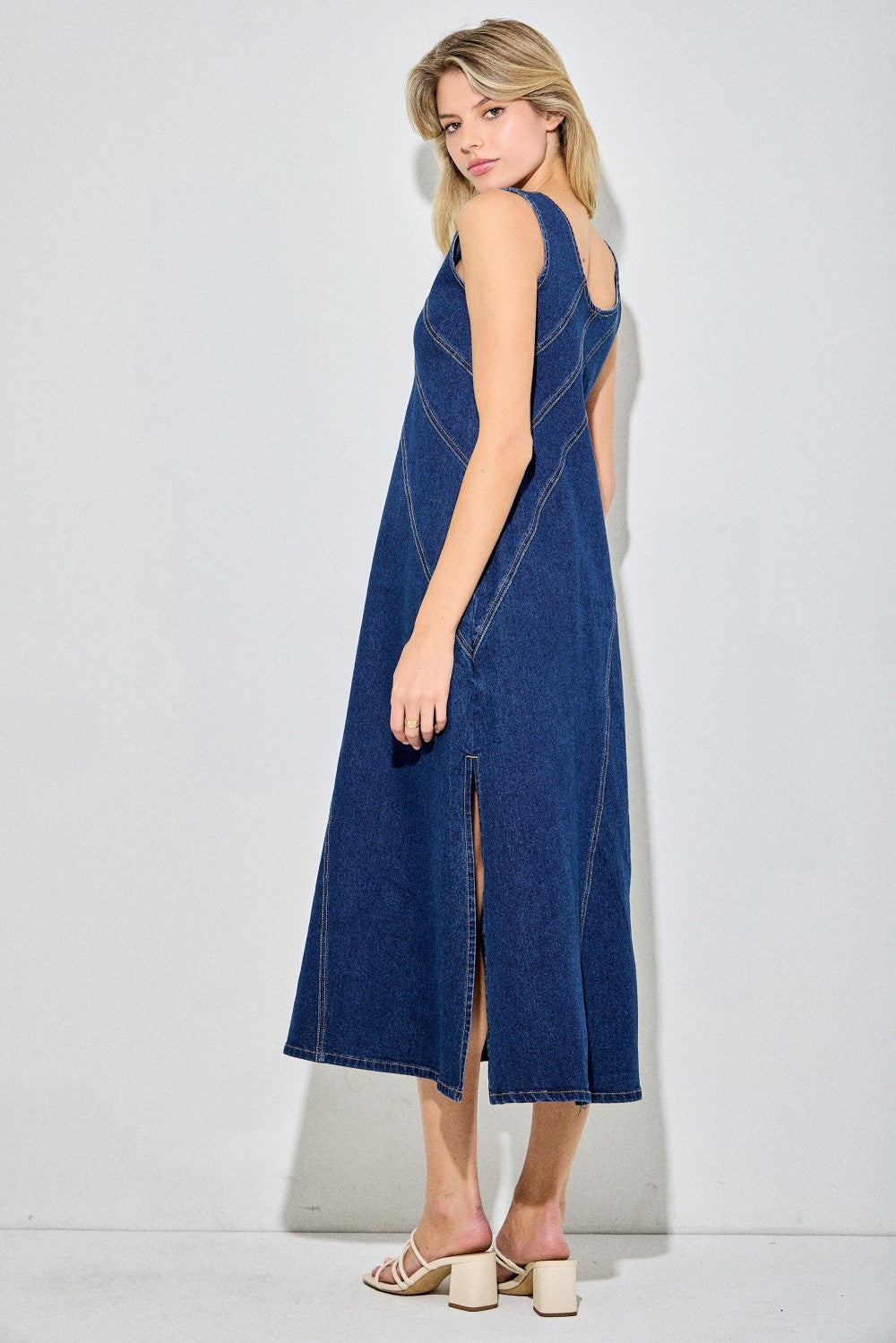 Sleeveless dark denim dress with angle detailing and a side slit. 