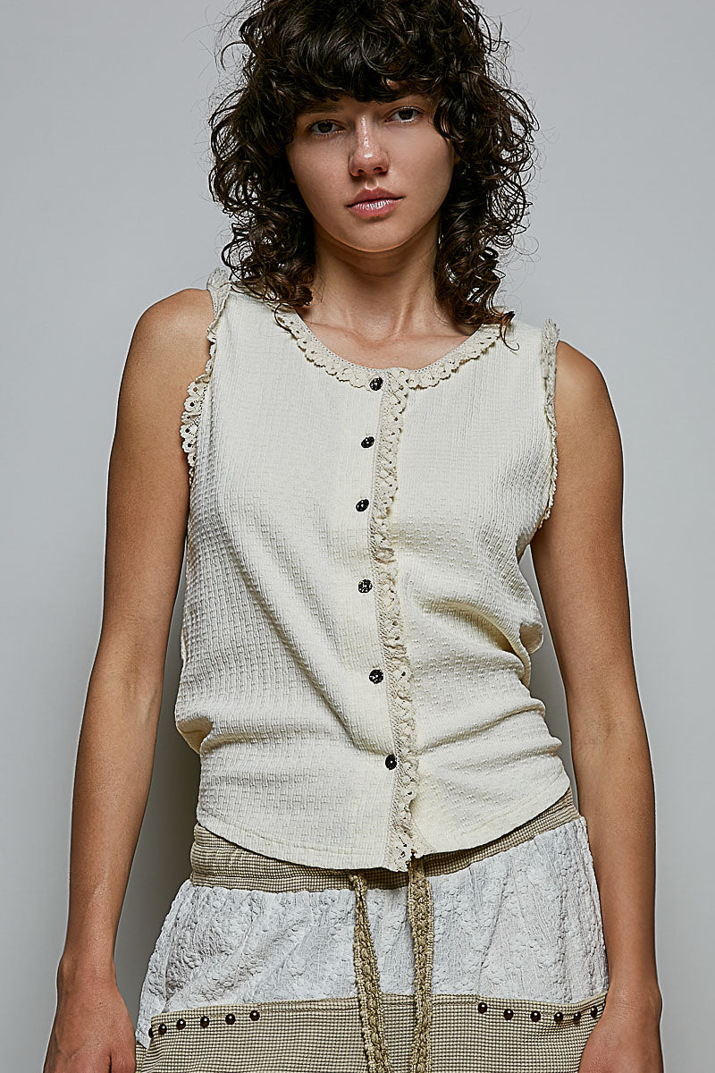 A women's sleeveless cream textured waffle-knit top featuring a button-front closure and delicate eyelet lace trimming along the round neckline and armholes.