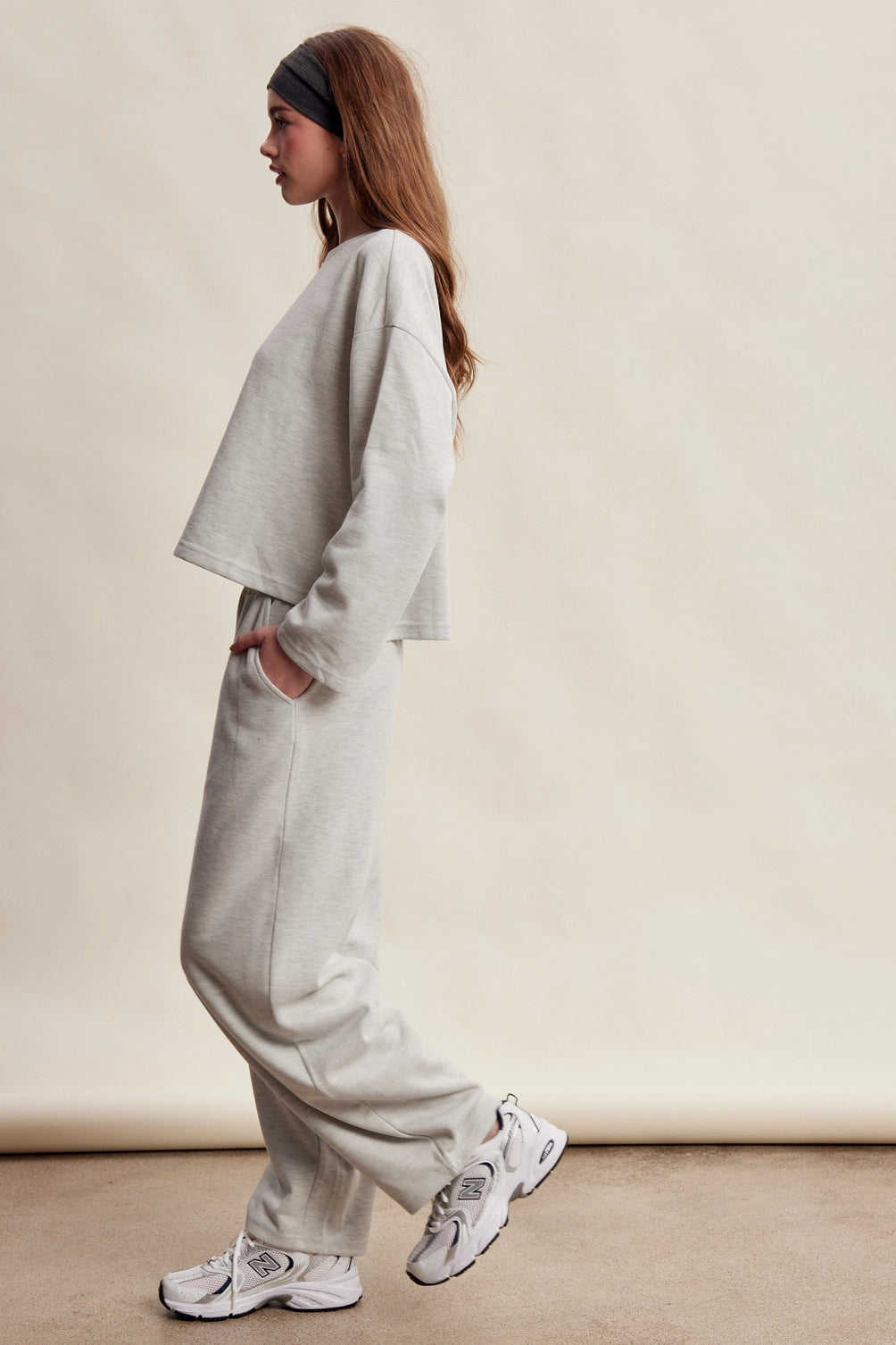 A women's heather gray two-piece stretch cotton lounge set featuring a long-sleeve crewneck top and matching high-waisted relaxed wide-leg pants.