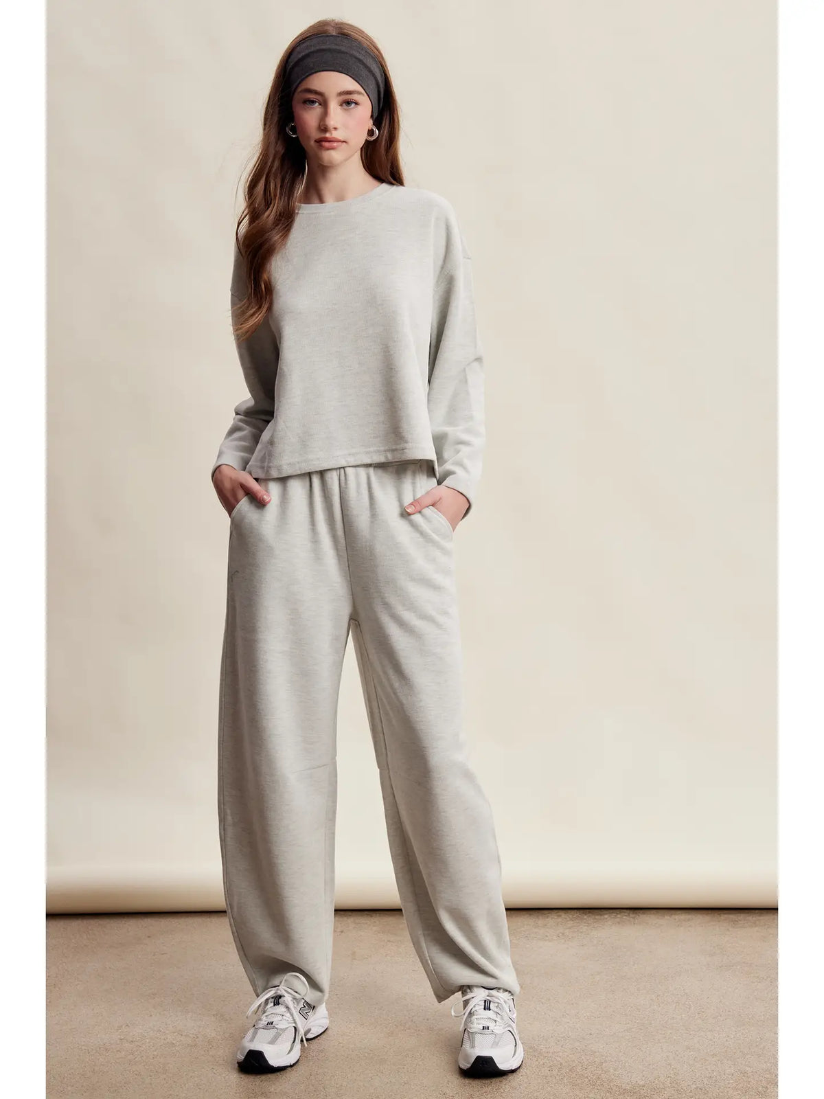 A women's heather gray two-piece stretch cotton lounge set featuring a long-sleeve crewneck top and matching high-waisted relaxed wide-leg pants.