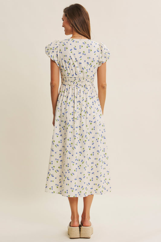 V-neck dress with puff sleeves, defined waist, pockets, and blueberry print. 