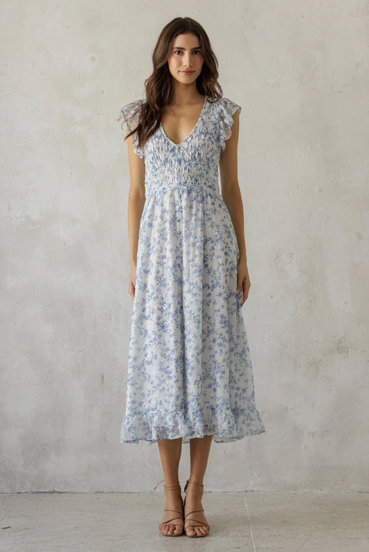 A dainty blue and white floral midi dress featuring a stretchy smocked bodice, delicate flutter ruffle sleeves, and a breezy tiered skirt.