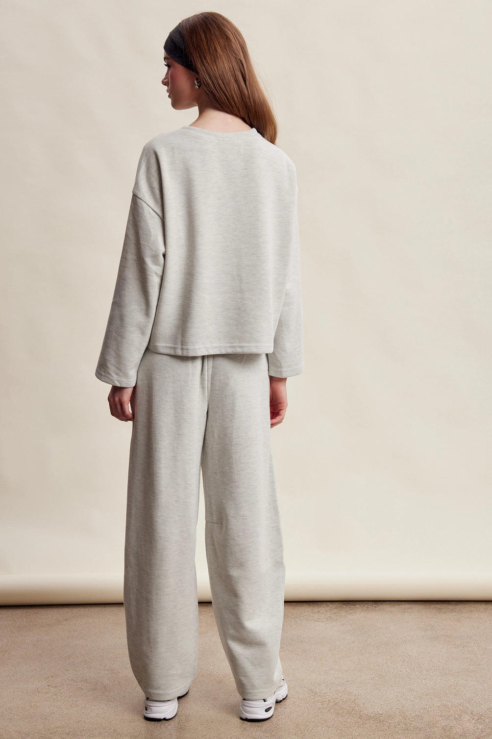 A women's heather gray two-piece stretch cotton lounge set featuring a long-sleeve crewneck top and matching high-waisted relaxed wide-leg pants.