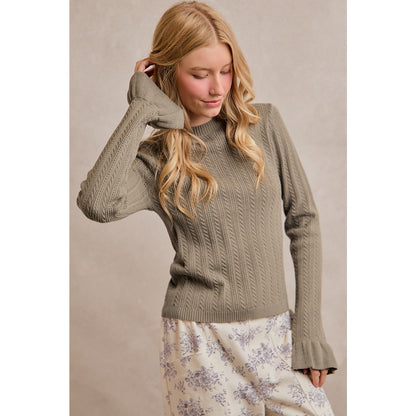 A women's olive green long-sleeve cable-knit sweater featuring a mock neckline, ribbed hem, and ruffled flare knit cuffs.