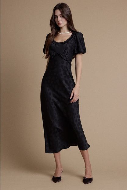 A women's black satin jacquard polka dot midi dress featuring short puff sleeves, a scoop neckline with ruffle trim, and a high empire waistline.