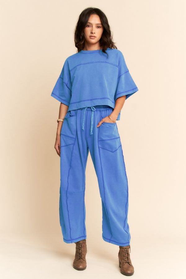 A women's two-piece lounge set in washed marina blue featuring a short-sleeve cropped top with exposed seam lines and matching high-rise wide-leg pants with a drawstring waist and utility patch pockets.