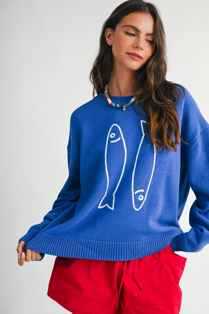 A women's royal blue long-sleeve knit crewneck sweater featuring a white embroidered sardine graphic on the front and ribbed trim along the collar, cuffs, and hem.
