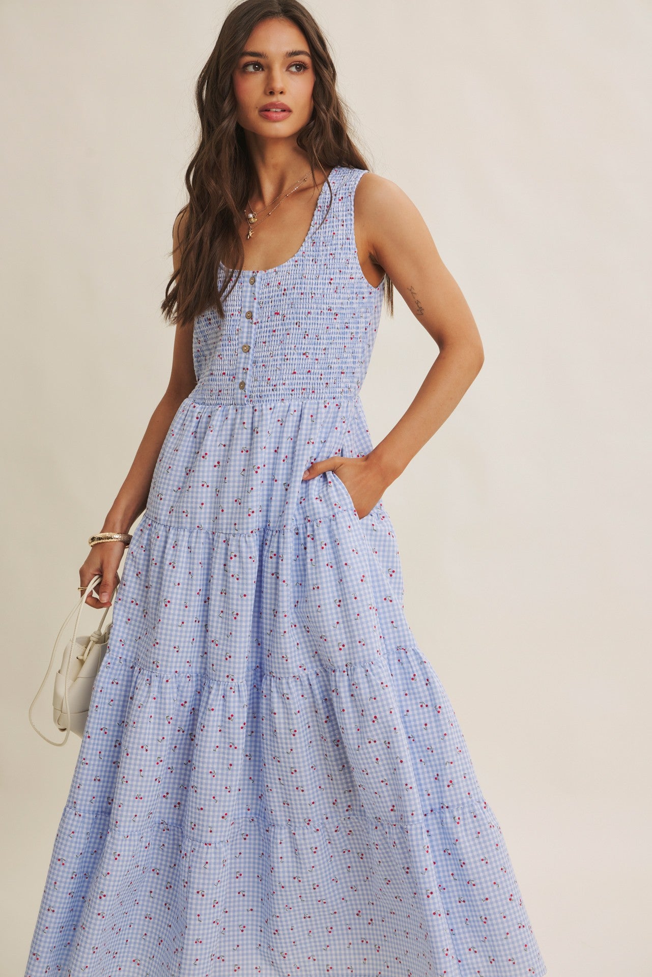 Cherry gingham print maxi dress in the color sky blue. The dress has a smocked bust, round neck, button-down detail, side pockets and comes lined. 