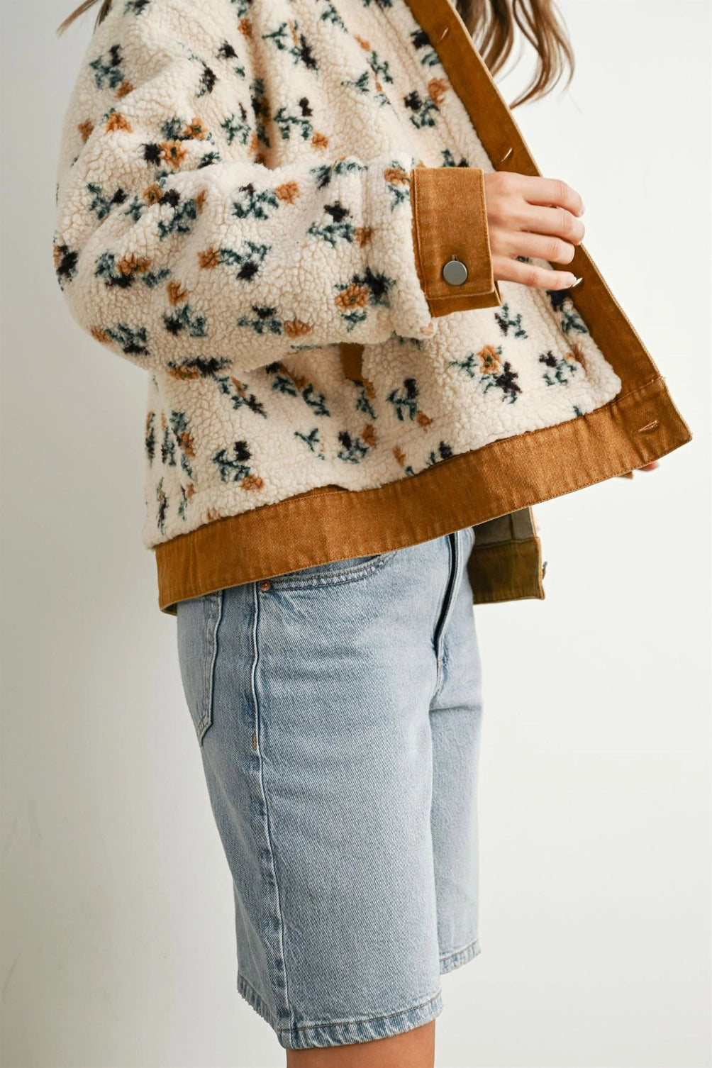 A women's cream floral printed plush sherpa fleece jacket featuring camel brown twill contrast trim, front button closures, and side pockets.