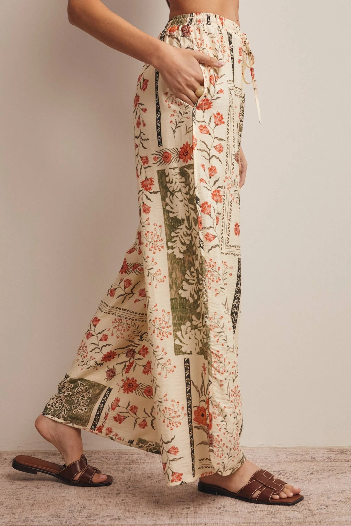 High-waisted wide-leg patchwork floral print pants in ecru, terracotta, and olive green featuring a comfortable elastic drawstring waistband and a relaxed silhouette.