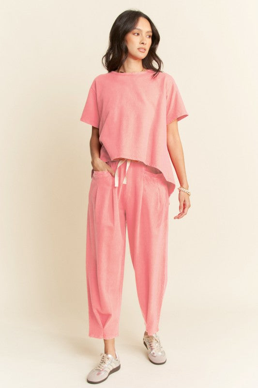 This two-piece cotton set features a hi-low relaxed tee with subtle back pleats and wide-leg drawstring pants with oversized pockets in pink. 