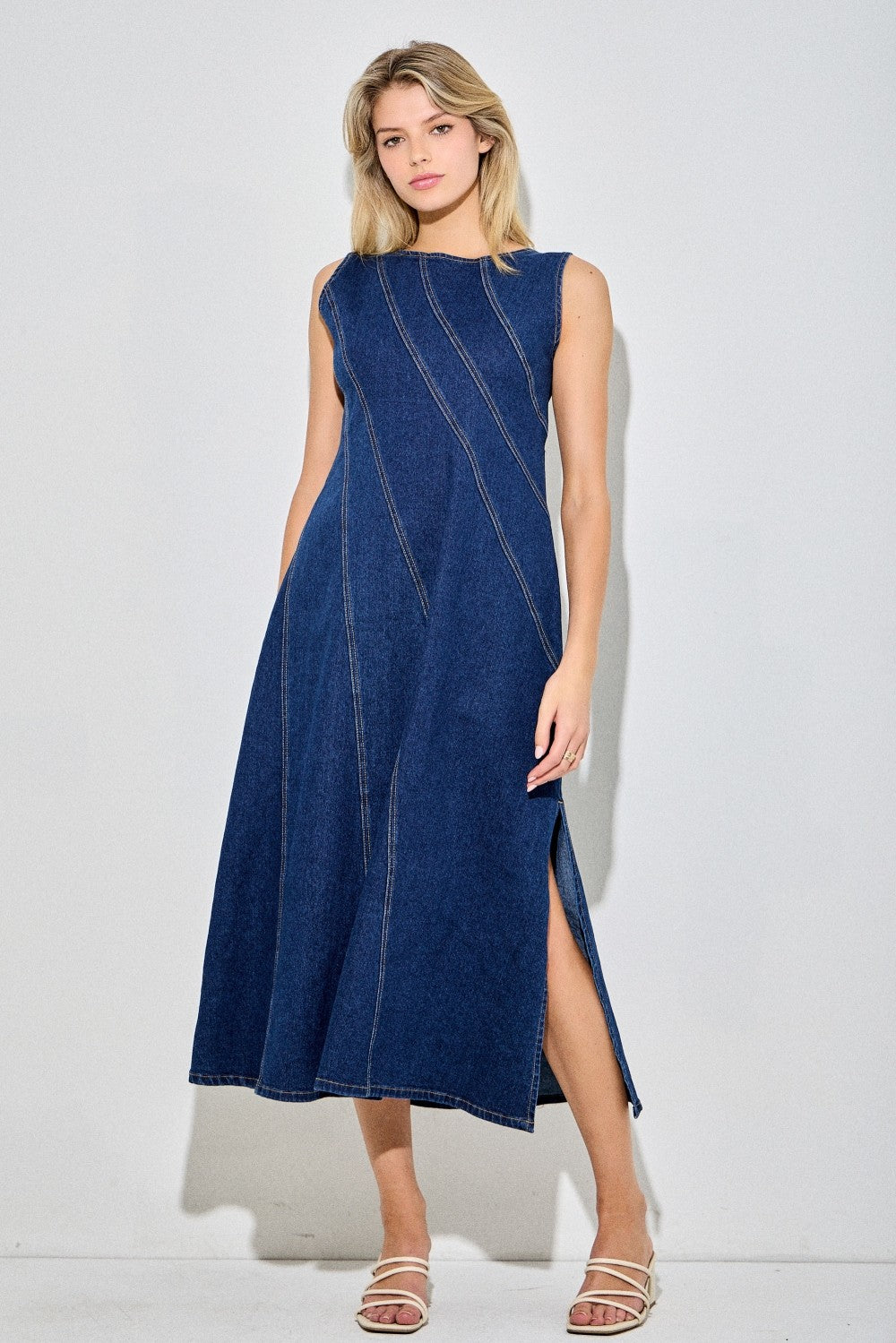 Sleeveless dark denim dress with angle detailing and a side slit. 