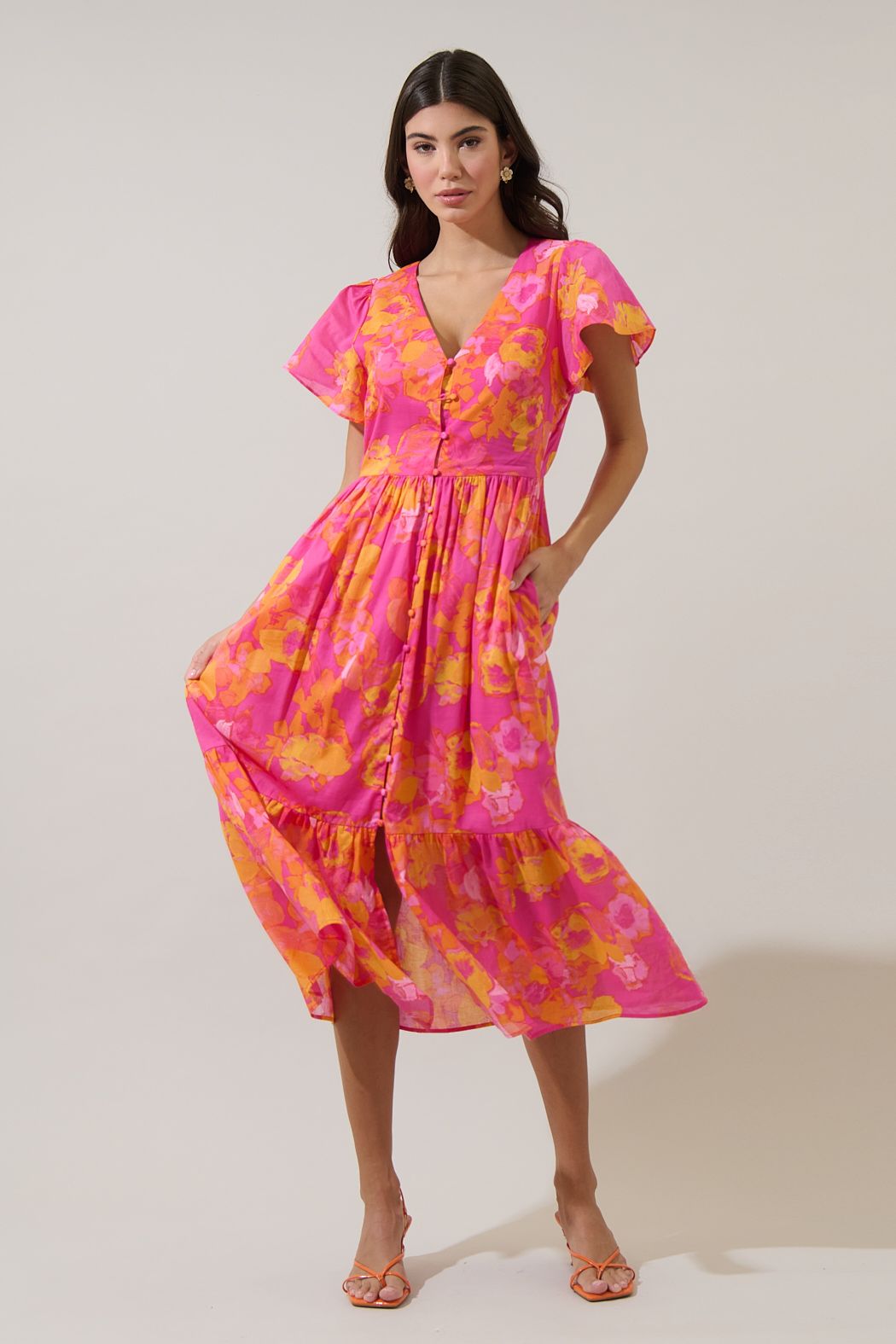 V-neck floral midi dress in orange and fuchsia with functional buttons and flutter sleeves. 