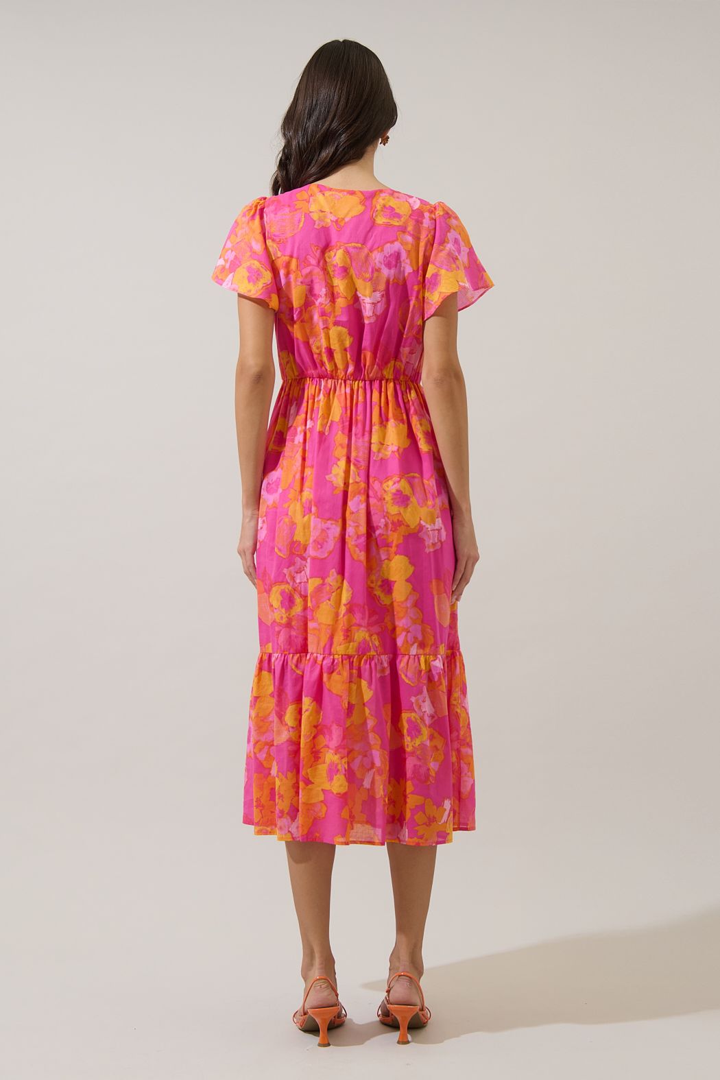 V-neck floral midi dress in orange and fuchsia with functional buttons and flutter sleeves. 