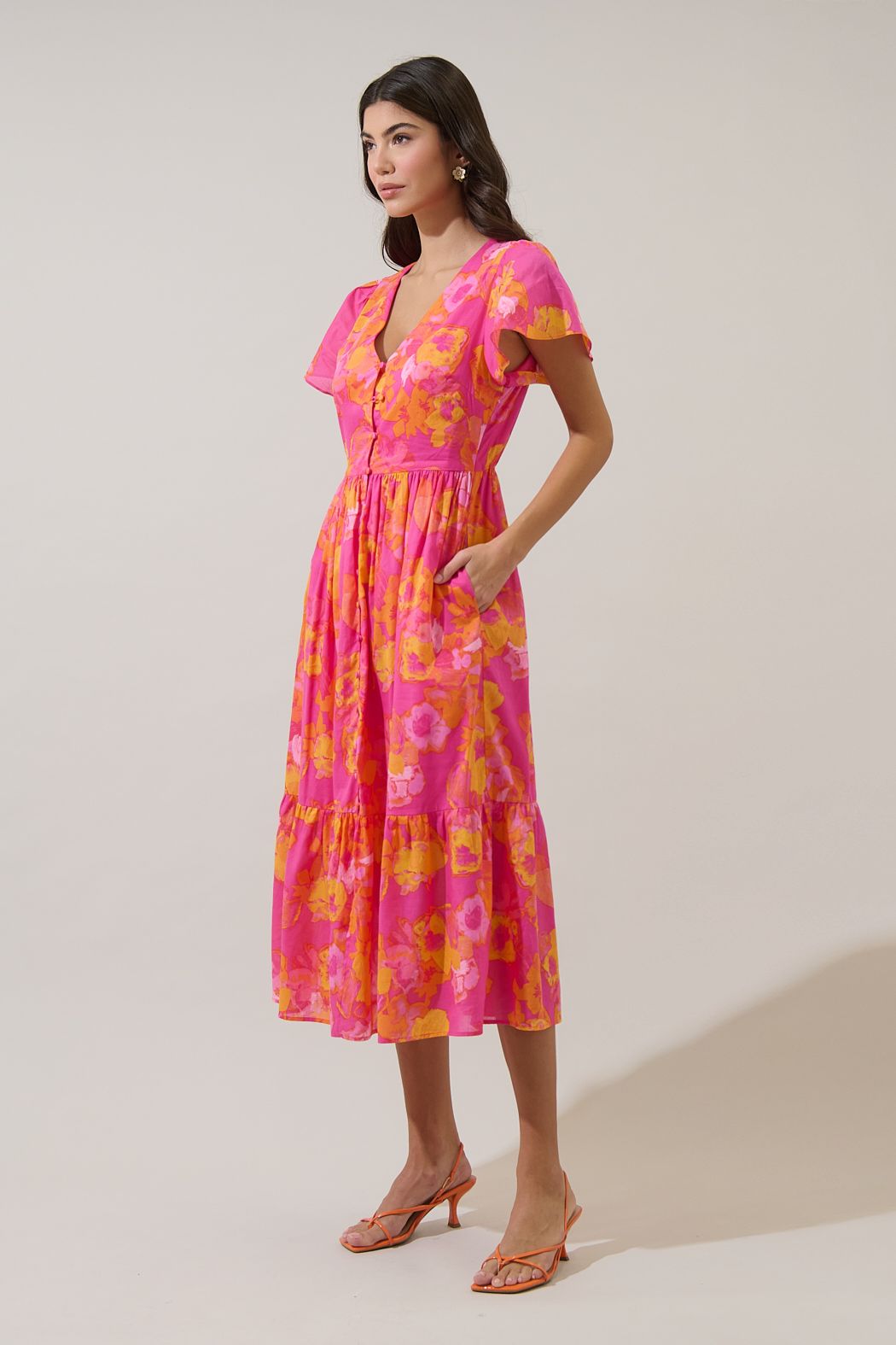 V-neck floral midi dress in orange and fuchsia with functional buttons and flutter sleeves. 
