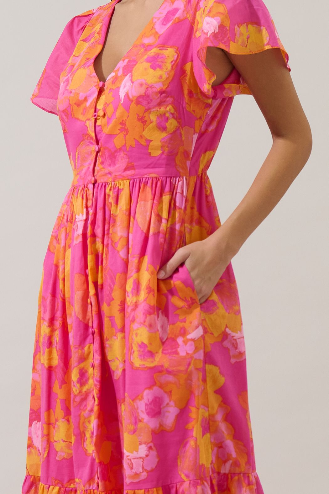 V-neck floral midi dress in orange and fuchsia with functional buttons, flutter sleeves, and pockets. 