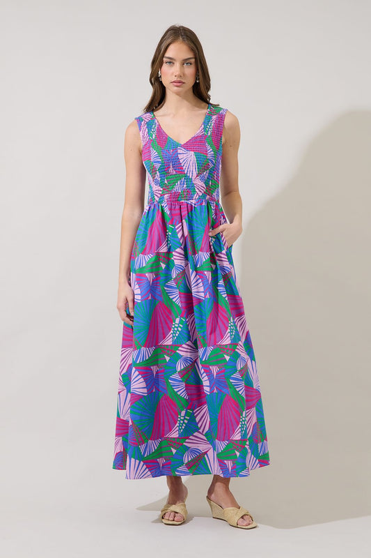 A sleeveless midi dress in a vibrant pink and blue tropical fan print featuring a stretchy smocked bodice, a V-neckline, and functional side pockets.